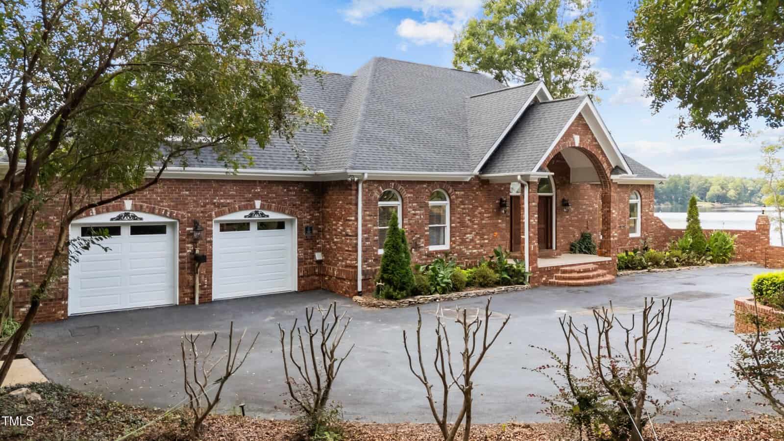 A brick house with a driveway and trees.