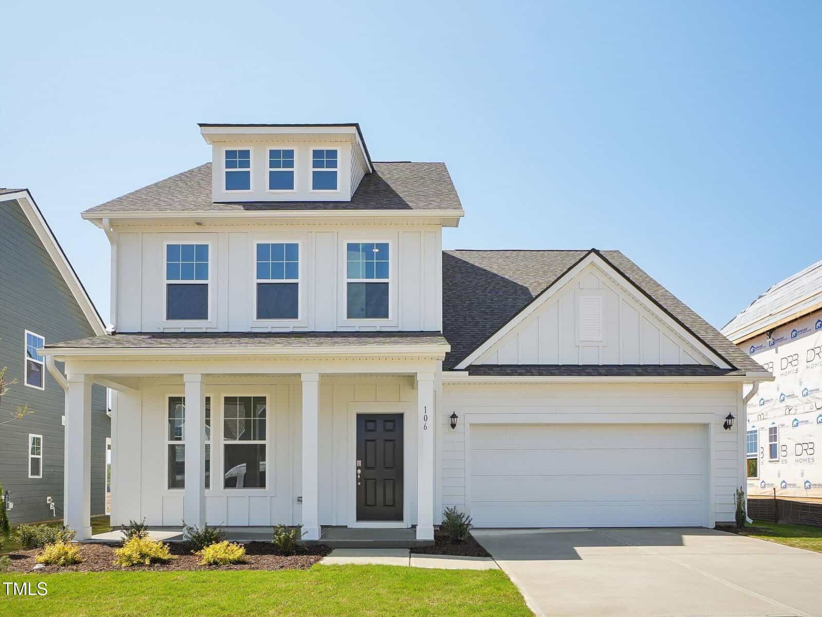 Two-story modern suburban house with white siding, a covered front porch, black front door, and attached two-car garage at 100 Copperleaf Court in Franklinton. The lawn is neatly trimmed, and the house is situated between two neighboring homes under a clear blue sky.