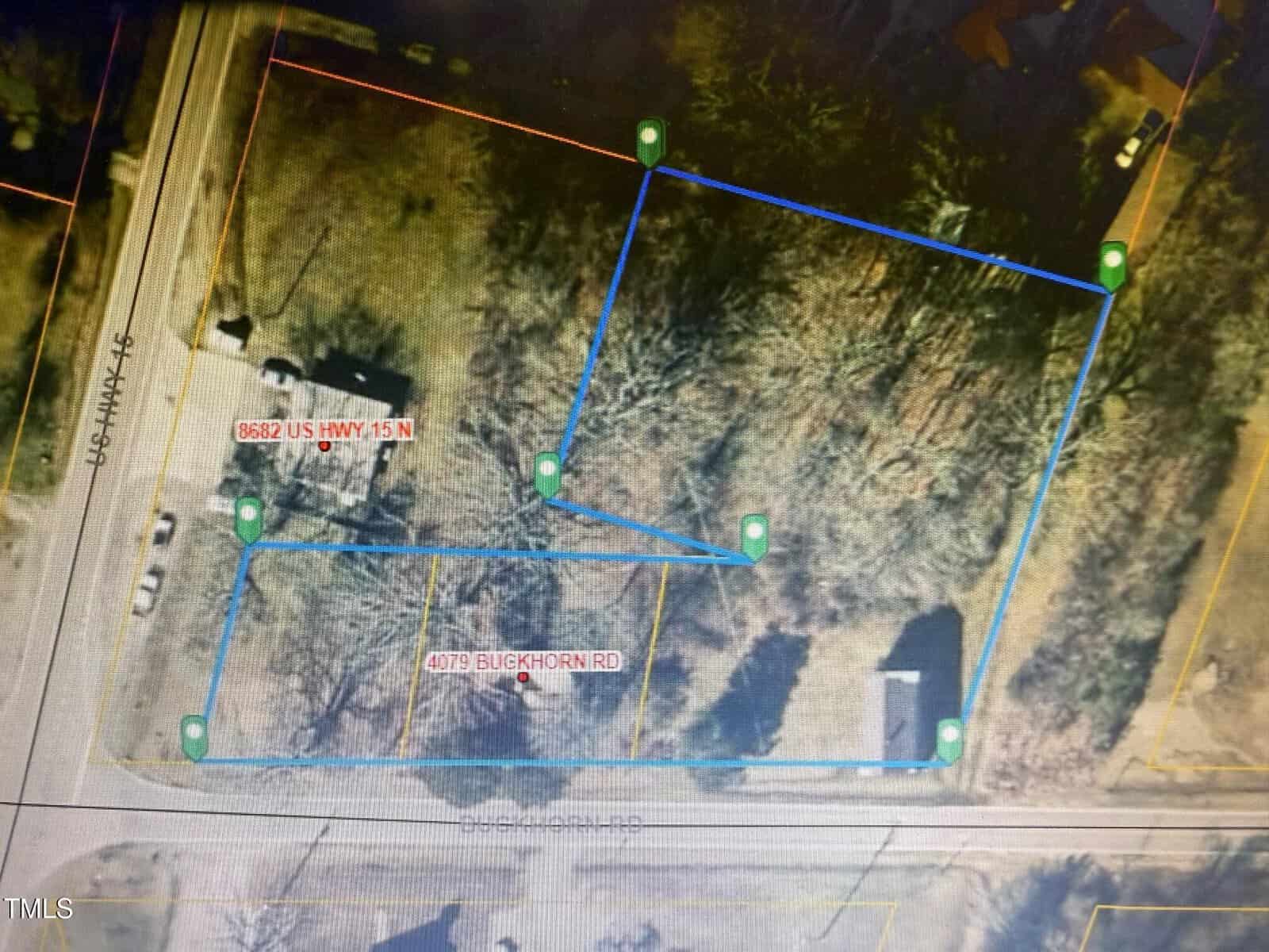 Aerial map view with property boundaries outlined in blue, labeled with addresses “5652 US HWY 15 N” and “4079 Buckhorn Rd,” showing streets, buildings, and wooded areas.