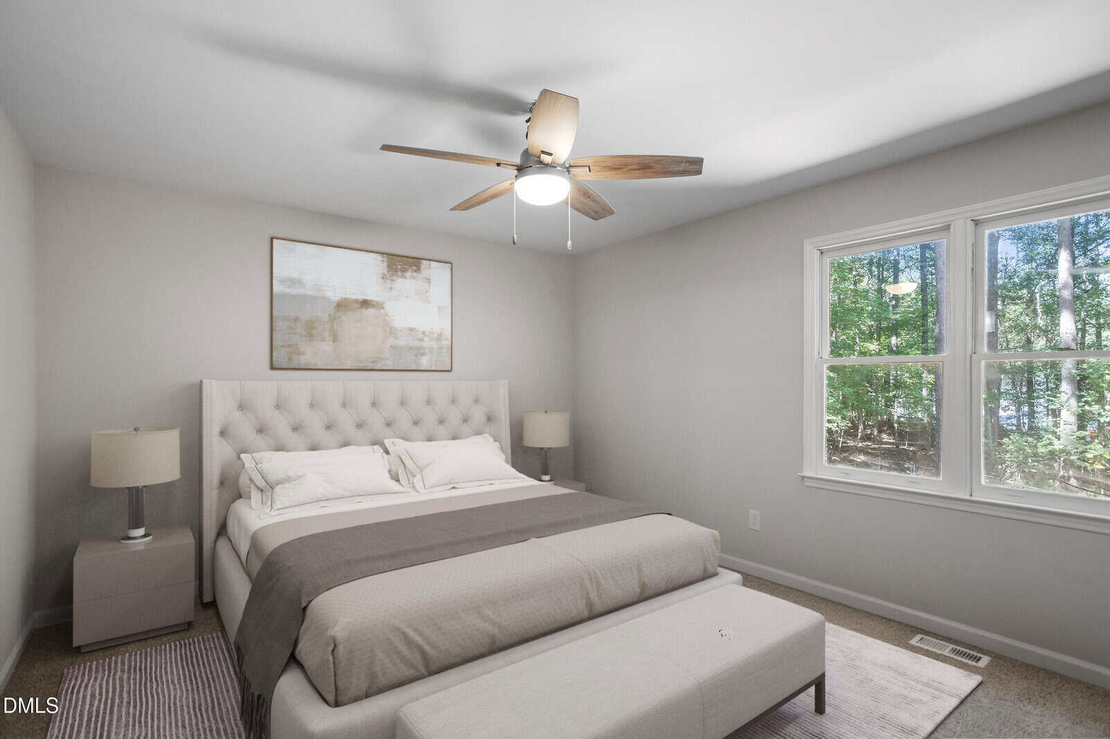 A modern bedroom with a large bed, two bedside tables with lamps, a bench at the foot of the bed, abstract wall art above the headboard, and a window showing a view of trees outside.