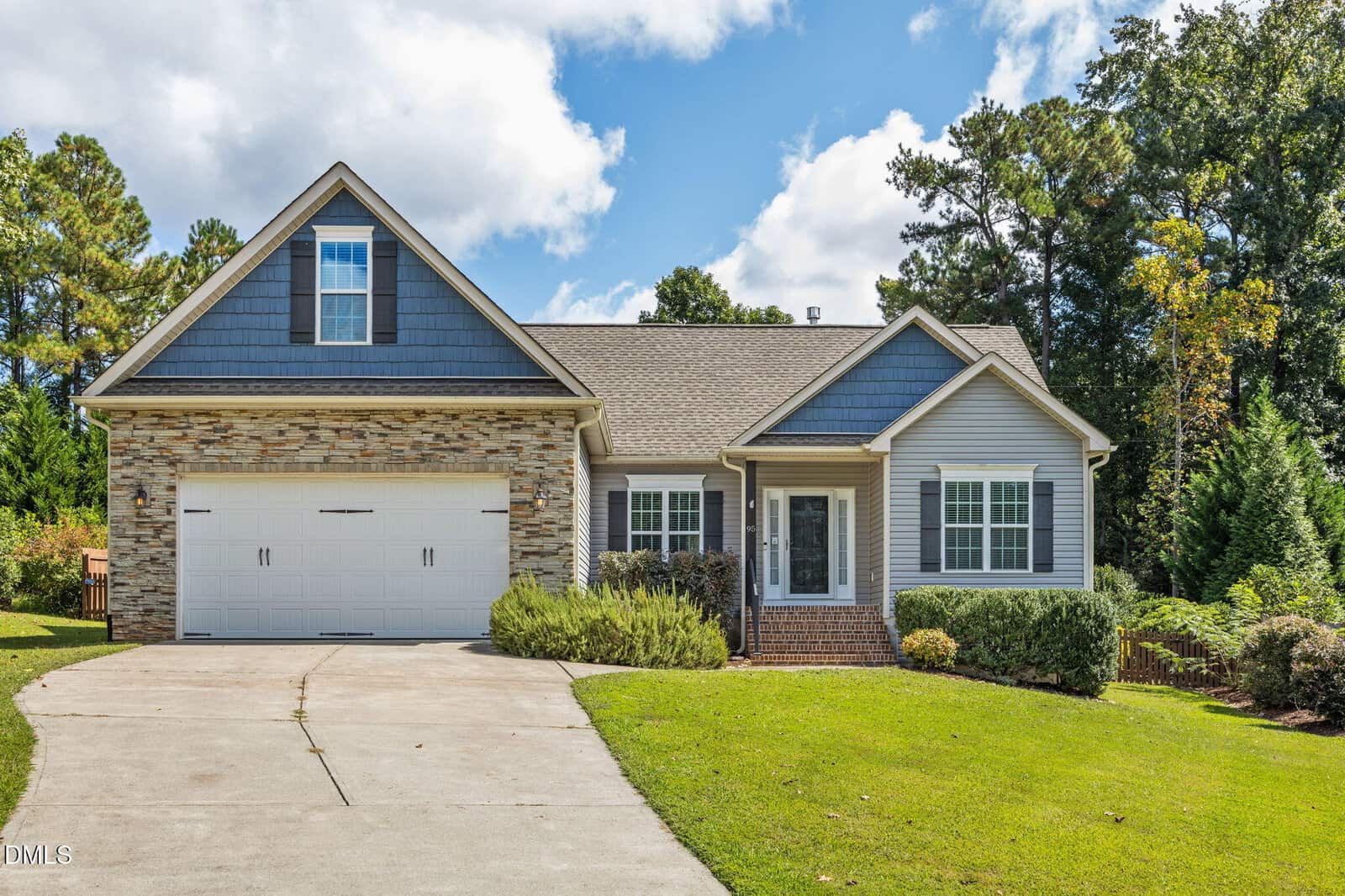 Charming single-story suburban house located at 95 Cullen Court, Franklinton, featuring a mixed stone and siding exterior, an attached two-car garage, gabled roof, welcoming front porch, and a curved driveway. The home is surrounded by a green lawn and mature trees under a partly cloudy sky.