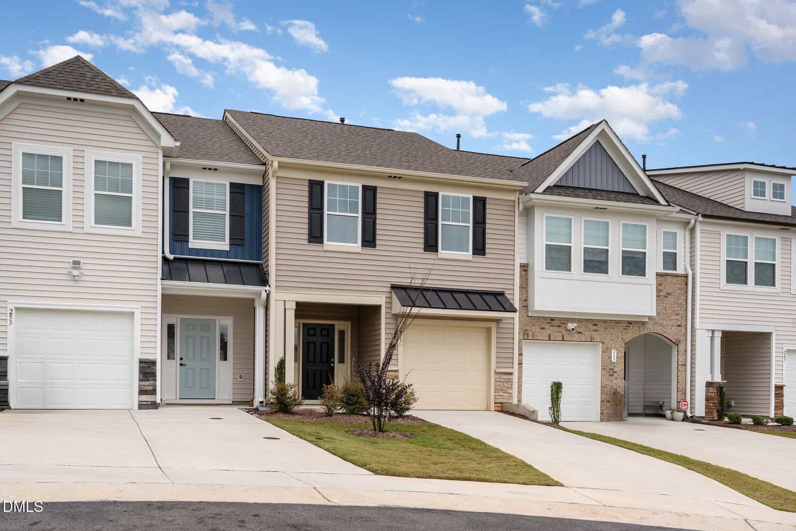 Row of modern two-story townhouses with beige and white siding, black shutters, and single-car garages along 251 Blandford Street in Franklinton. Concrete driveways lead to each garage. Small lawns and young shrubs are in front. Sky is partly cloudy.