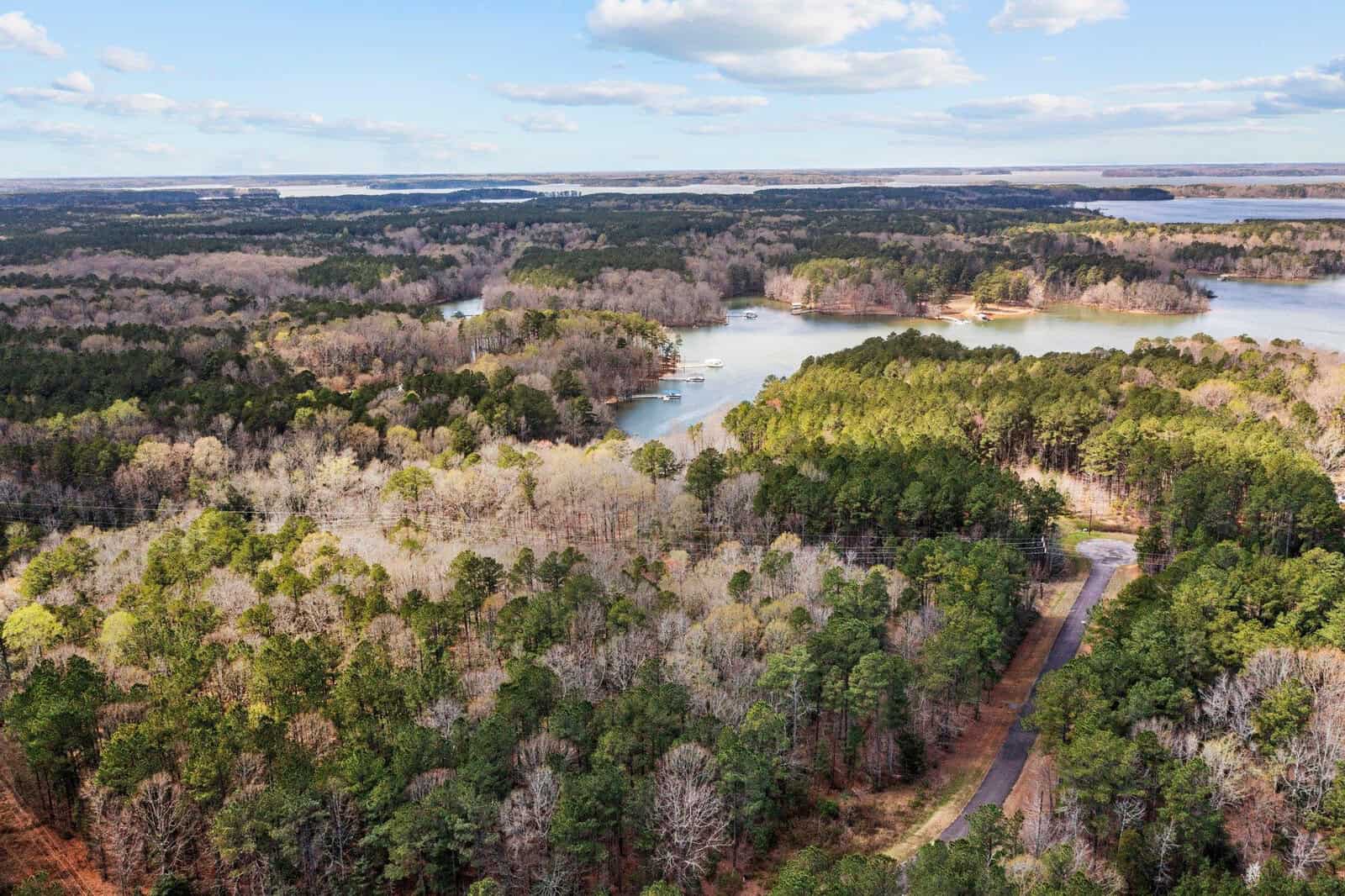 Aerial view of a forested area near Manson, with winding roads and a large lake featuring several coves. The trees are dense, and the sky is mostly clear with a few scattered clouds—Lot 11 Aruba Lane is nestled among the natural beauty.