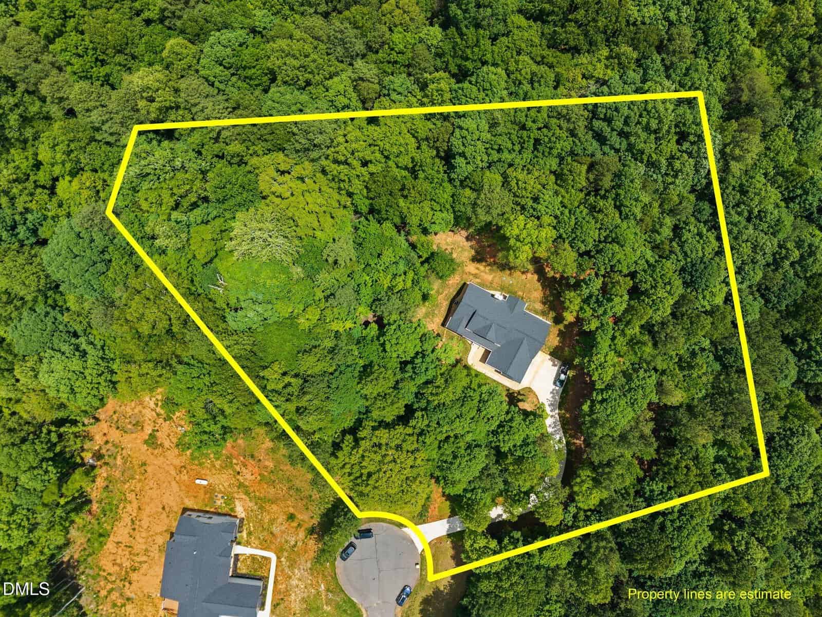 Aerial view of a wooded property outlined in yellow, showing a single house within the boundary near a cul-de-sac, with dense trees and another house nearby. Text in the corner notes property lines are estimates.