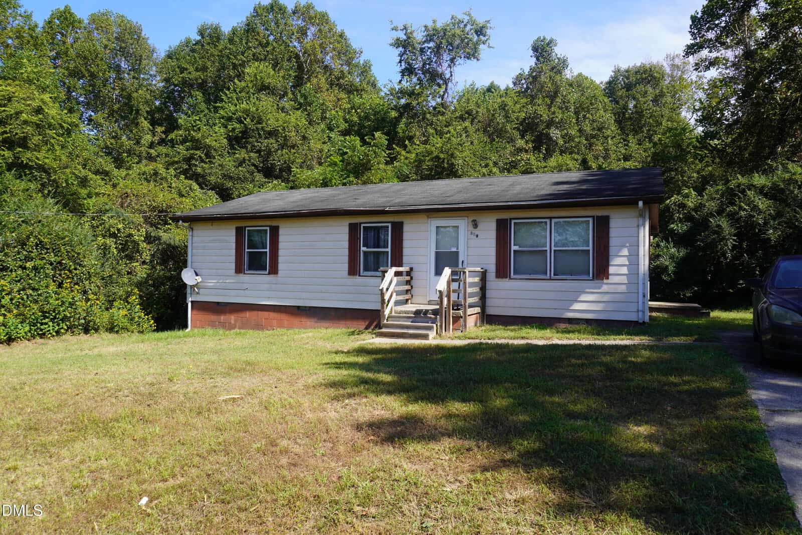 Single-story house at 179 Lynnbank Estates Road in Kittrell, featuring beige siding, a black roof, and a small front porch with steps; surrounded by grass lawn and trees, with a car partially visible on the right side.