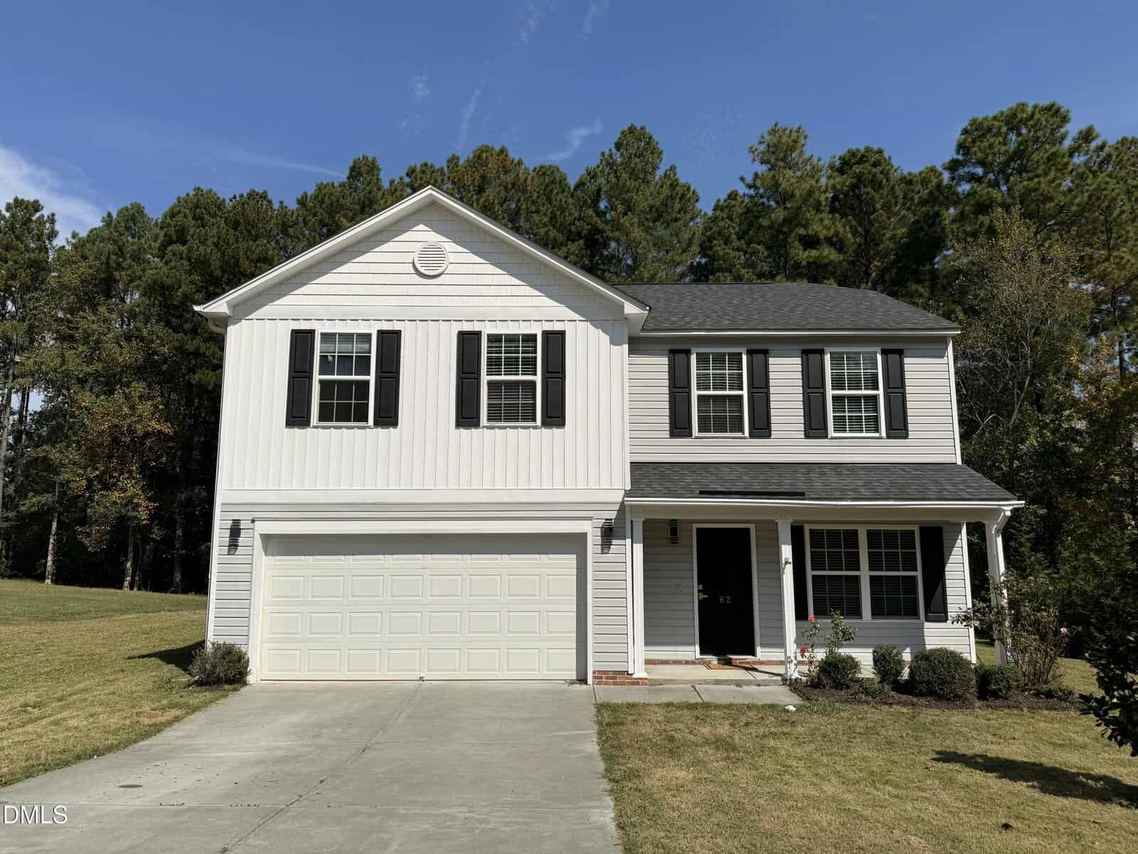 Charming two-story suburban house at 62 W Boulder Road, Henderson, with white siding, black shutters, a double garage, and a covered front porch. Enjoy a grassy yard and trees in the background under a clear sky.