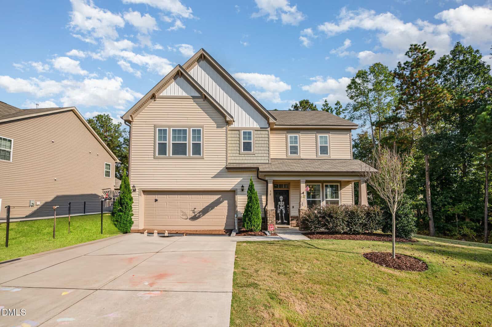 Charming two-story tan house at 30 Waterview Way, Franklinton, featuring an attached two-car garage, covered front porch, and manicured lawn. A small tree is planted near the driveway. The home is nestled in a suburban neighborhood with mature trees and blue sky in the background.