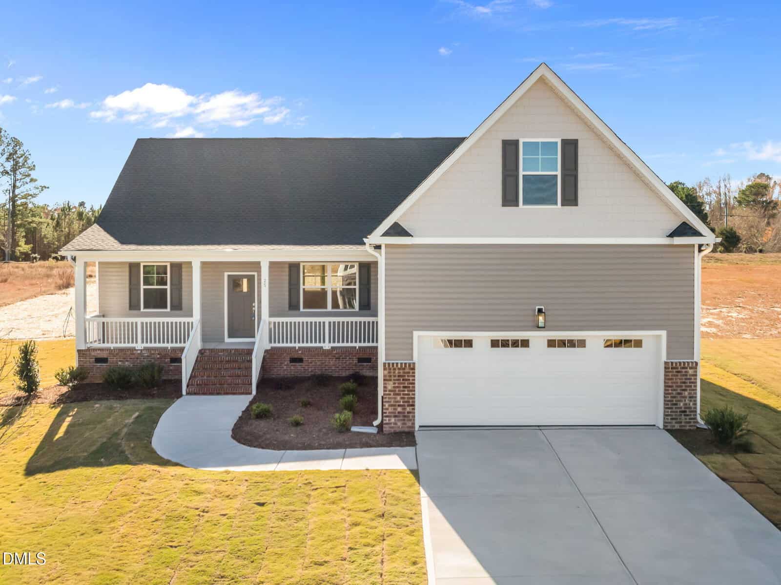 Single-story house with gray siding, white trim, front porch, gabled roof, and attached two-car garage, set on a neatly landscaped lawn with a clear blue sky in the background.