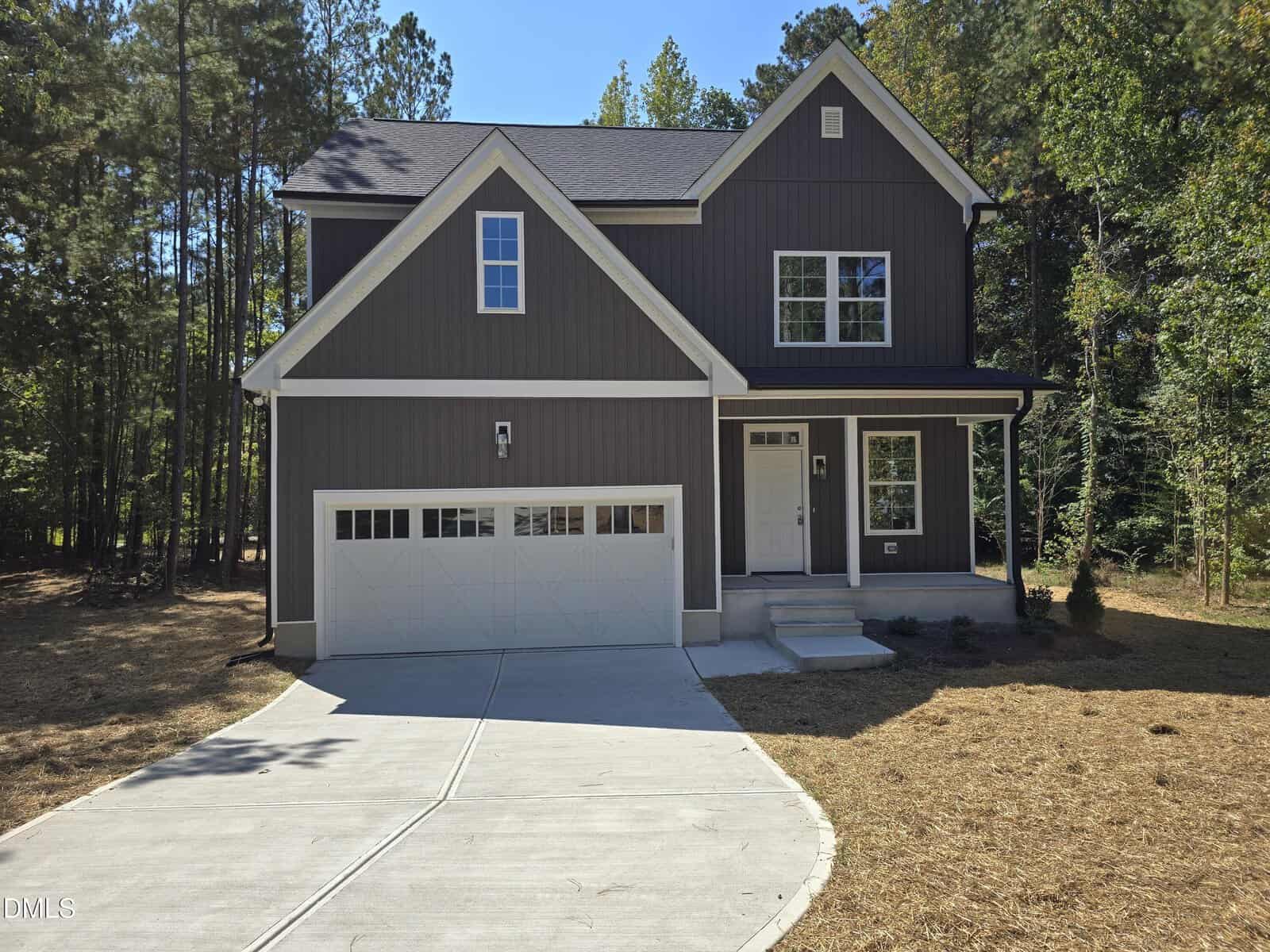 Two-story modern house at 3638 Wild Orchid Court, Wake Forest, with dark gray siding, white trim, and a double garage. The curved driveway leads to the front porch with white columns and steps, all surrounded by trees on a sunny day.