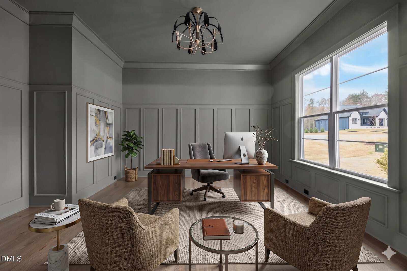 Modern home office with gray paneled walls, large window, wooden desk with computer, beige armchairs, neutral rug, and wall art. Natural light fills the room, and there are houses visible outside.