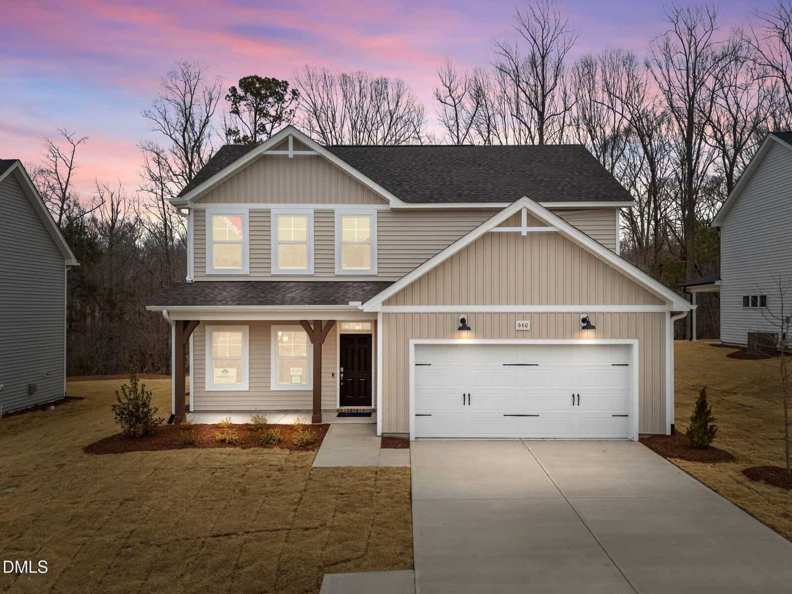 A two-story modern suburban house with beige siding, white trim, and a double garage located at 660 Husketh Road, Youngsville. The house is lit from inside at dusk, with a concrete driveway and a simple front yard. Leafless trees are visible in the background.
