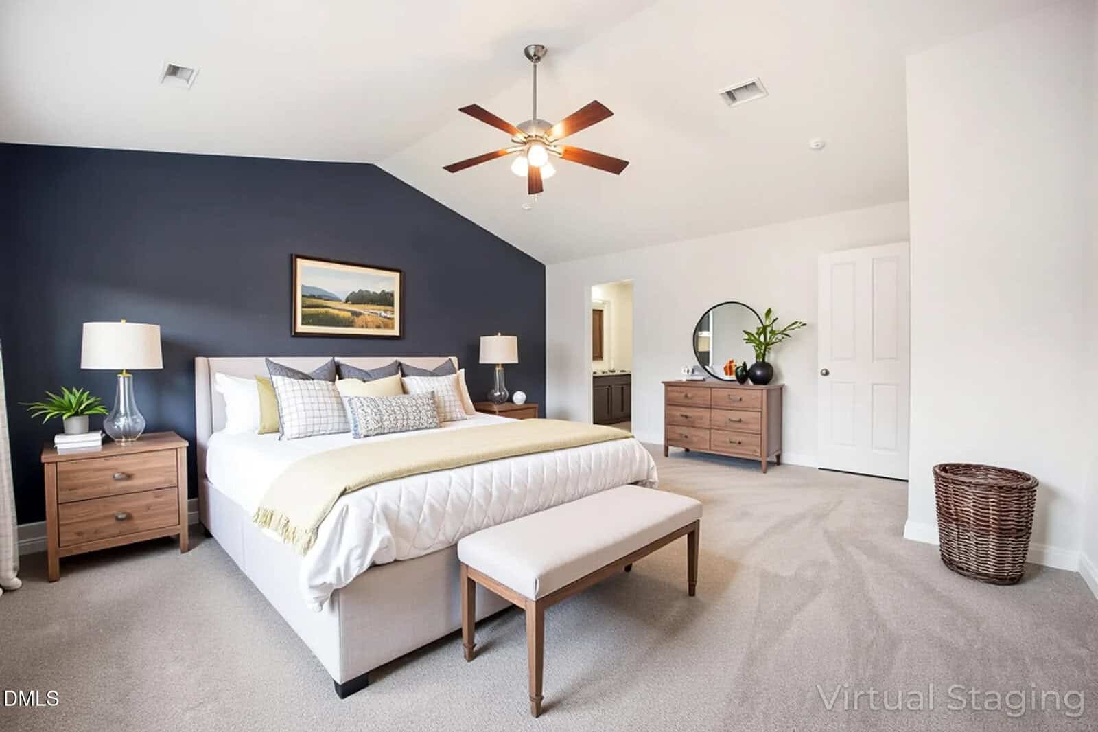 A modern bedroom with a bed, bench, two nightstands, lamps, a dresser with a mirror, and a laundry basket. The room has neutral colors, a dark accent wall, carpeted floor, and a ceiling fan with lights.