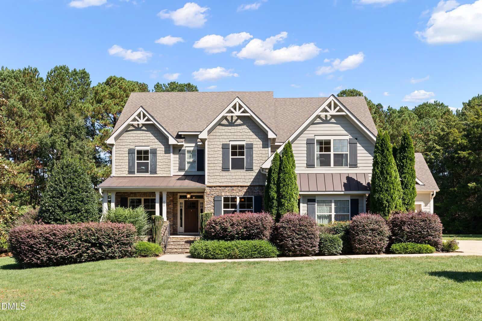 Located at 690 Hawthorne Place in Creedmoor, this two-story suburban house features gray siding, stone accents, white trim, multiple gables, a covered front porch with steps, manicured shrubs, and a large green lawn with trees behind.