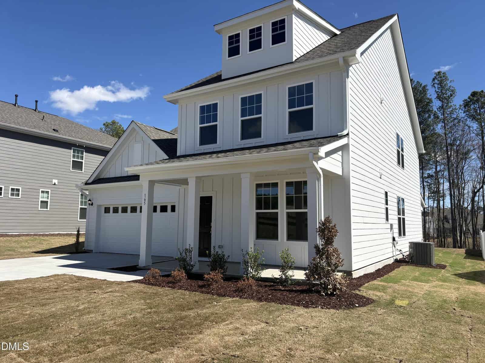 A modern two-story white house located at 165 Sugar Pine Drive Lot 149 in Franklinton features a welcoming front porch, attached garage, and a neatly landscaped yard that shines on a sunny day. Large windows and dark roof shingles complete the contemporary design.