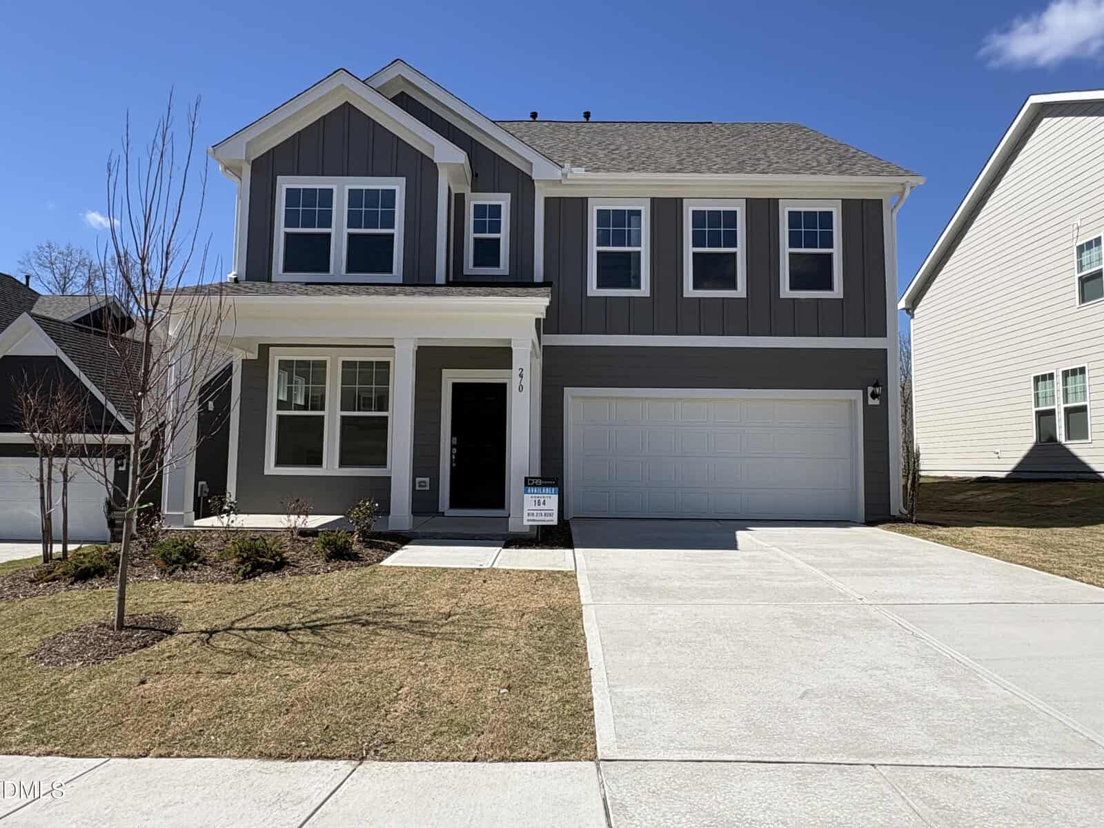 Two-story modern house at 270 Sugar Pine Drive, Franklinton, with dark gray siding, white trim, and a covered front porch. Features a two-car garage on the right, a small front yard with young trees, and a "For Sale" sign by the entrance.
