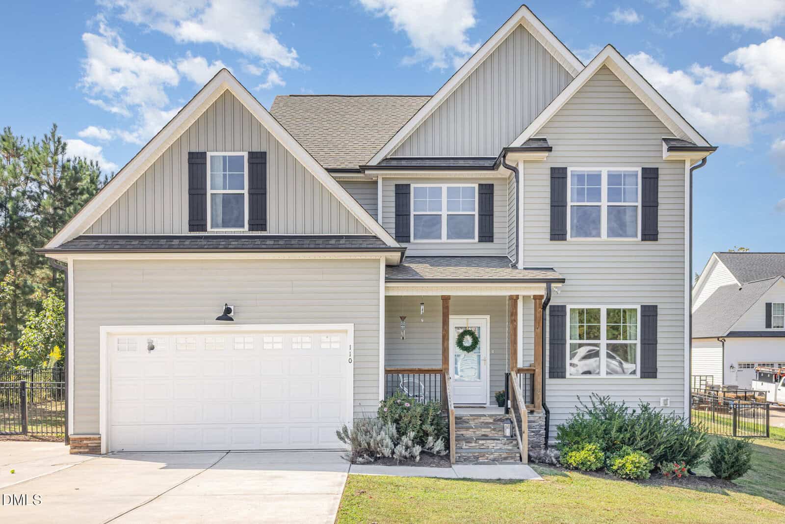Located at 110 Sorrel Drive in Franklinton, this two-story gray house features white trim, black shutters, a double garage, and a stone walkway to the front porch adorned with a green wreath. Shrubs and a green lawn complete the inviting curb appeal.