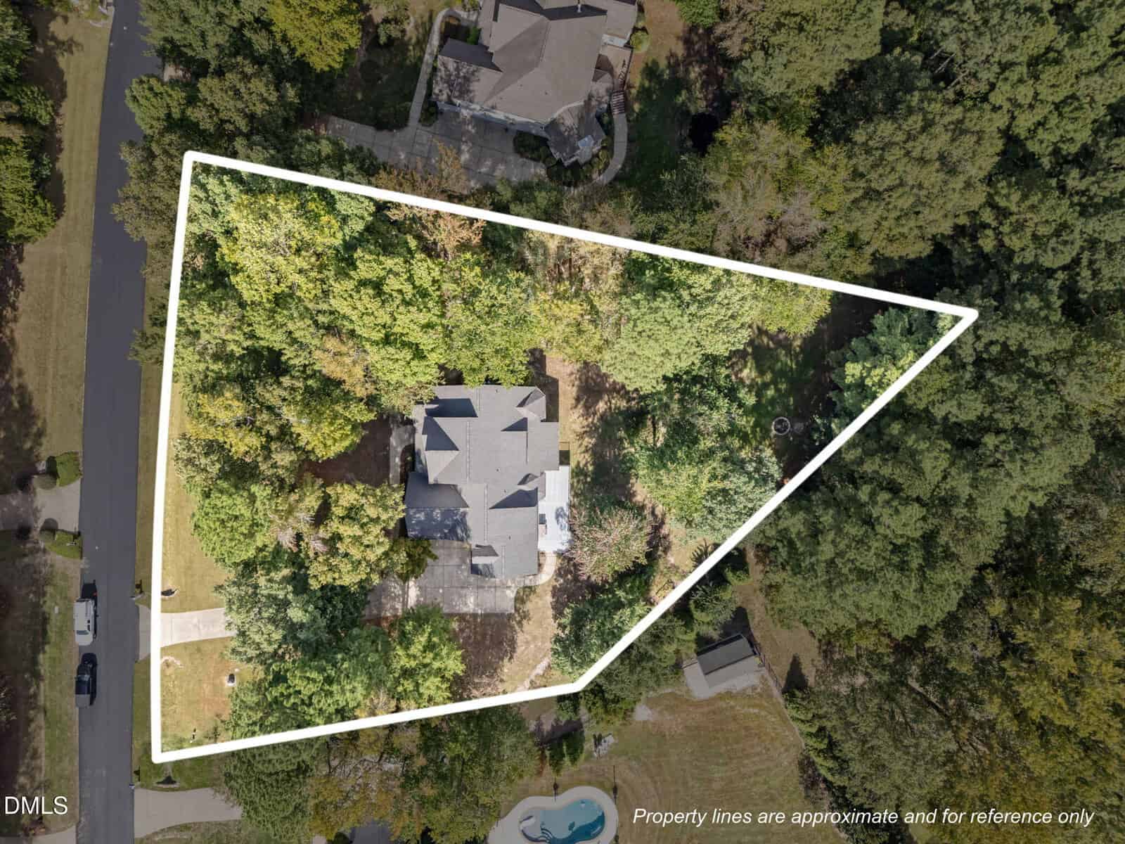 Aerial view of a house surrounded by trees within white property boundary lines, set in a residential neighborhood. The property features a driveway, lawn, and is bordered by streets and neighboring homes.