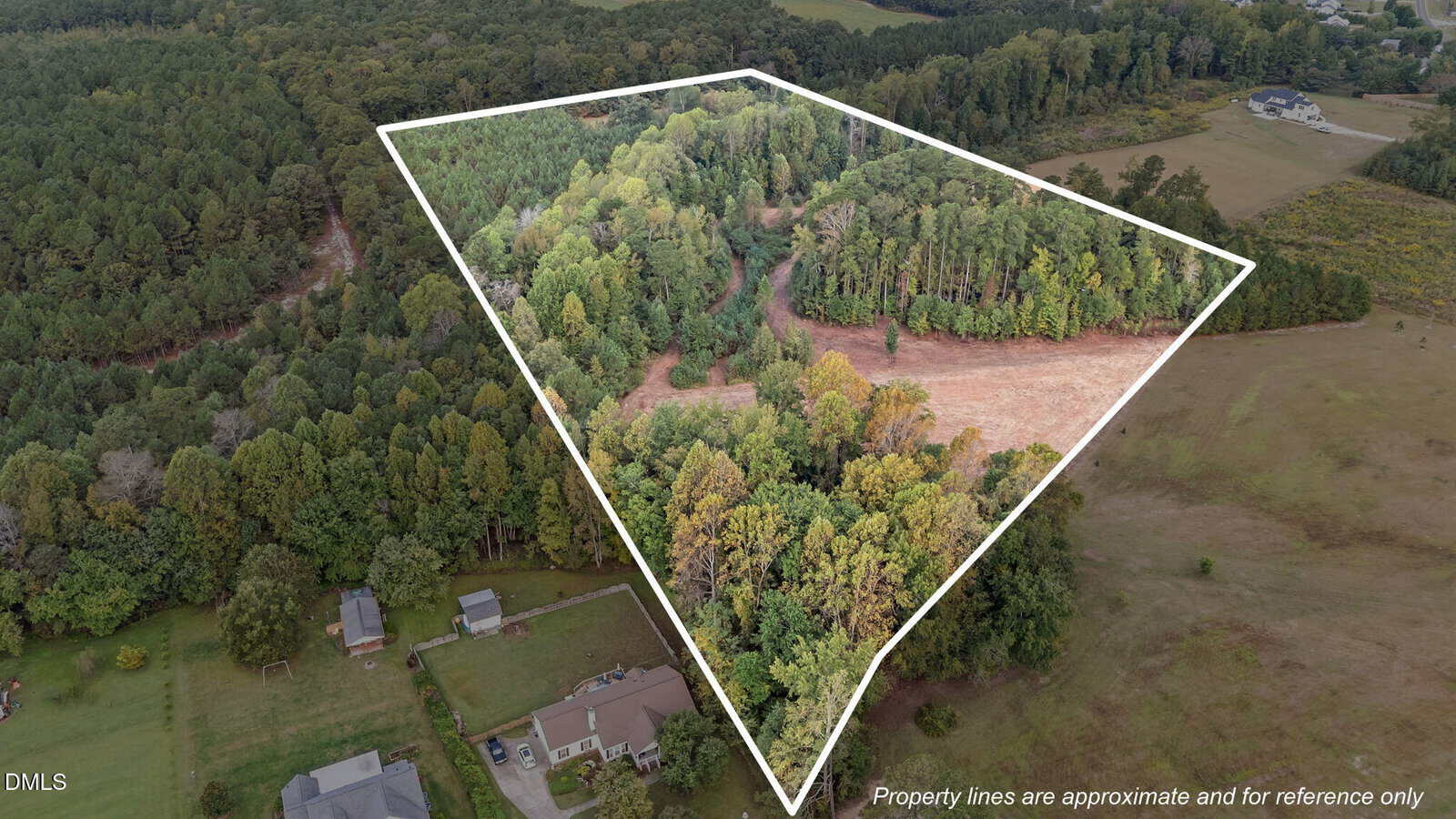 Aerial view of 305 Leghorn Drive in Zebulon outlined in white, showing dense trees, a dirt path, and cleared areas. Surrounded by other forested and open lands with nearby houses. Note: property lines are approximate.