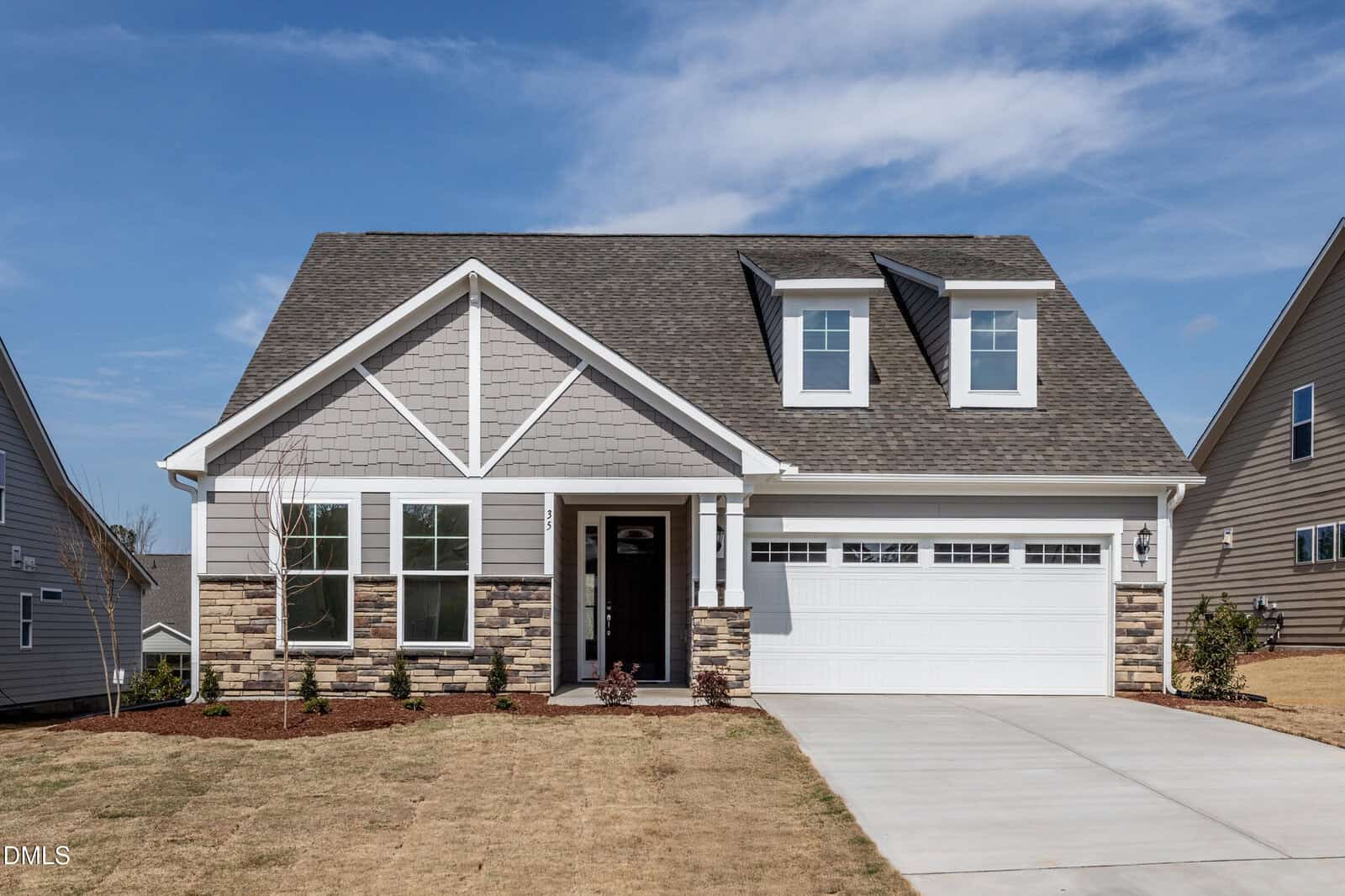A modern suburban house at 35 Slippery Elm Road, Youngsville, with gray siding, stone accents, white trim, a front porch, and a double garage. The driveway and front yard are neatly landscaped under a blue, partly cloudy sky.