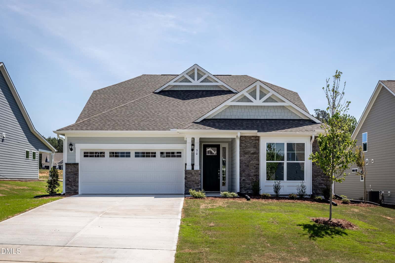 A modern, single-story suburban house at 30 Slippery Elm Road, Youngsville, with a gray shingle roof, stone and white siding exterior, two-car garage, black front door, and a small front yard with young trees and grass.