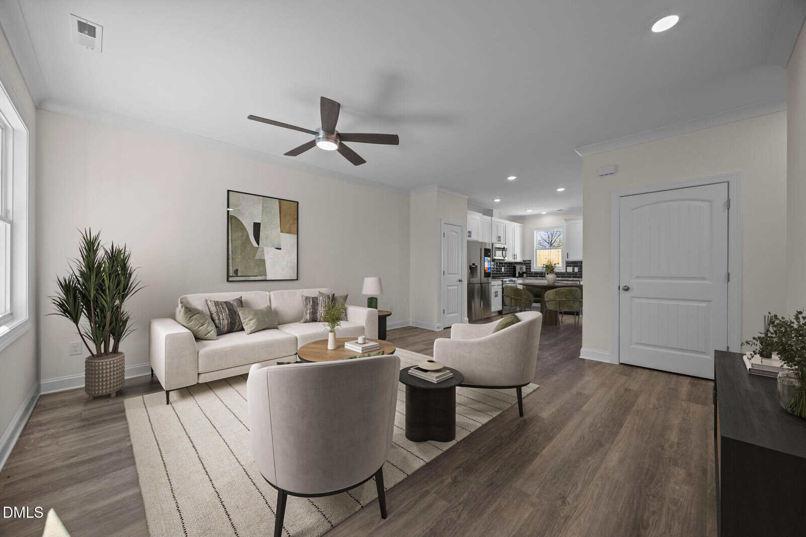 Modern living room with neutral decor, featuring a sofa, two chairs, a coffee table, a large plant, abstract wall art, and view into a kitchen with barstools. Wooden floors and white walls create a bright, open space.
