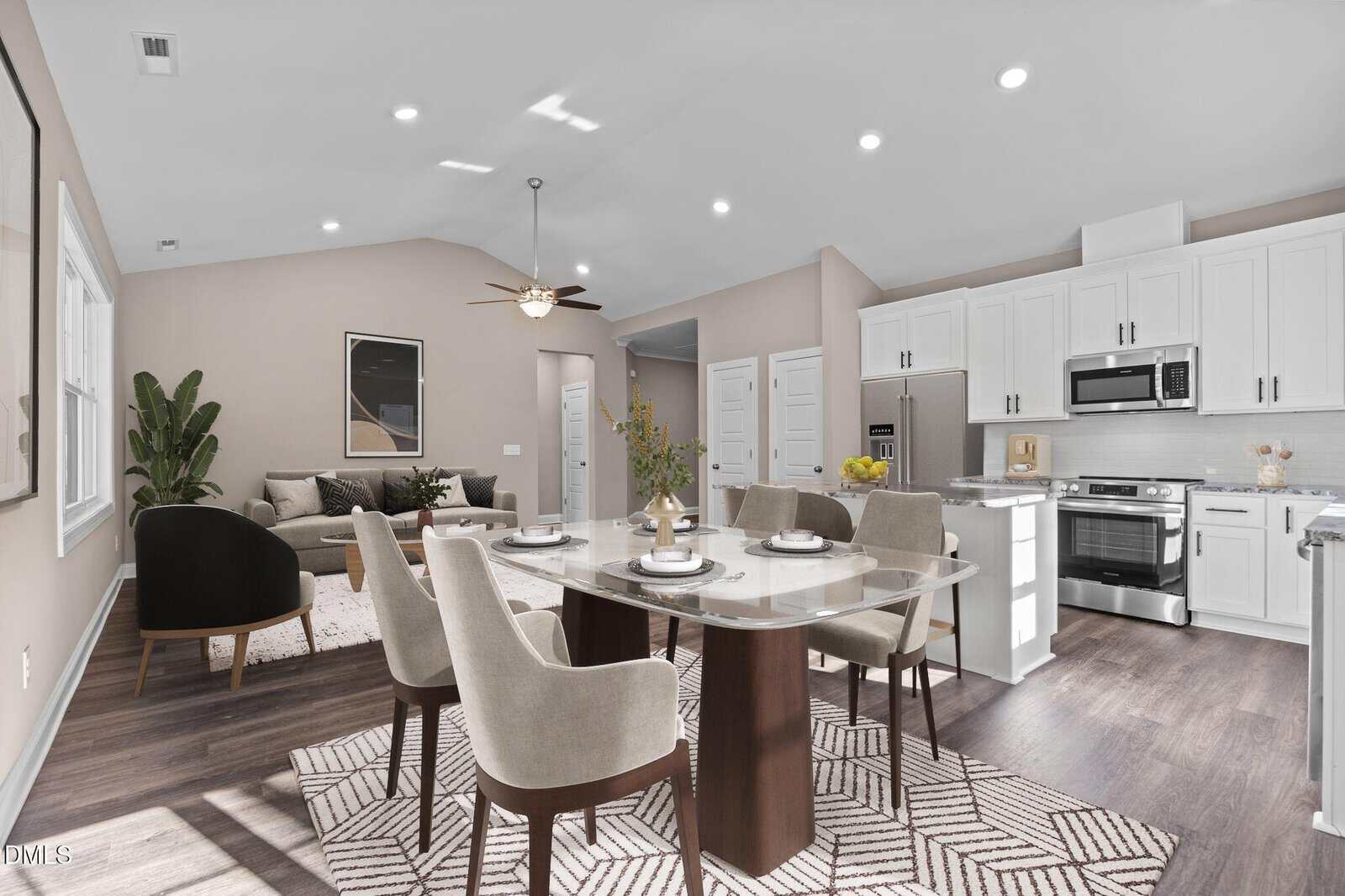 Modern open-concept kitchen and dining area with white cabinets, stainless steel appliances, a dining table set for four, and a cozy living space with a sofa and plant in the background.