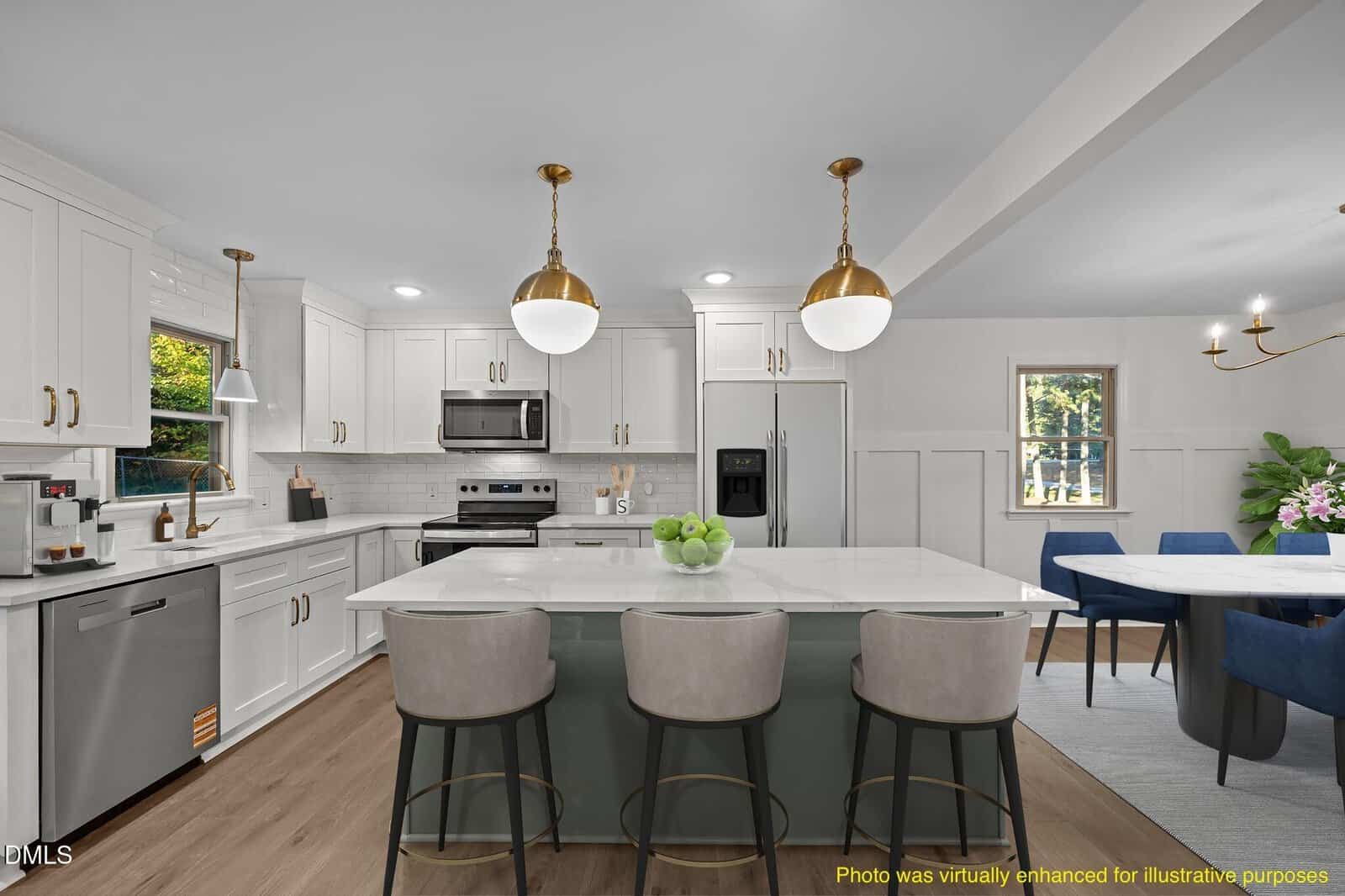 Modern kitchen with white cabinets, stainless steel appliances, and a large island with gray stools. Two gold pendant lights hang above the island. A dining area with blue chairs is visible in the background.