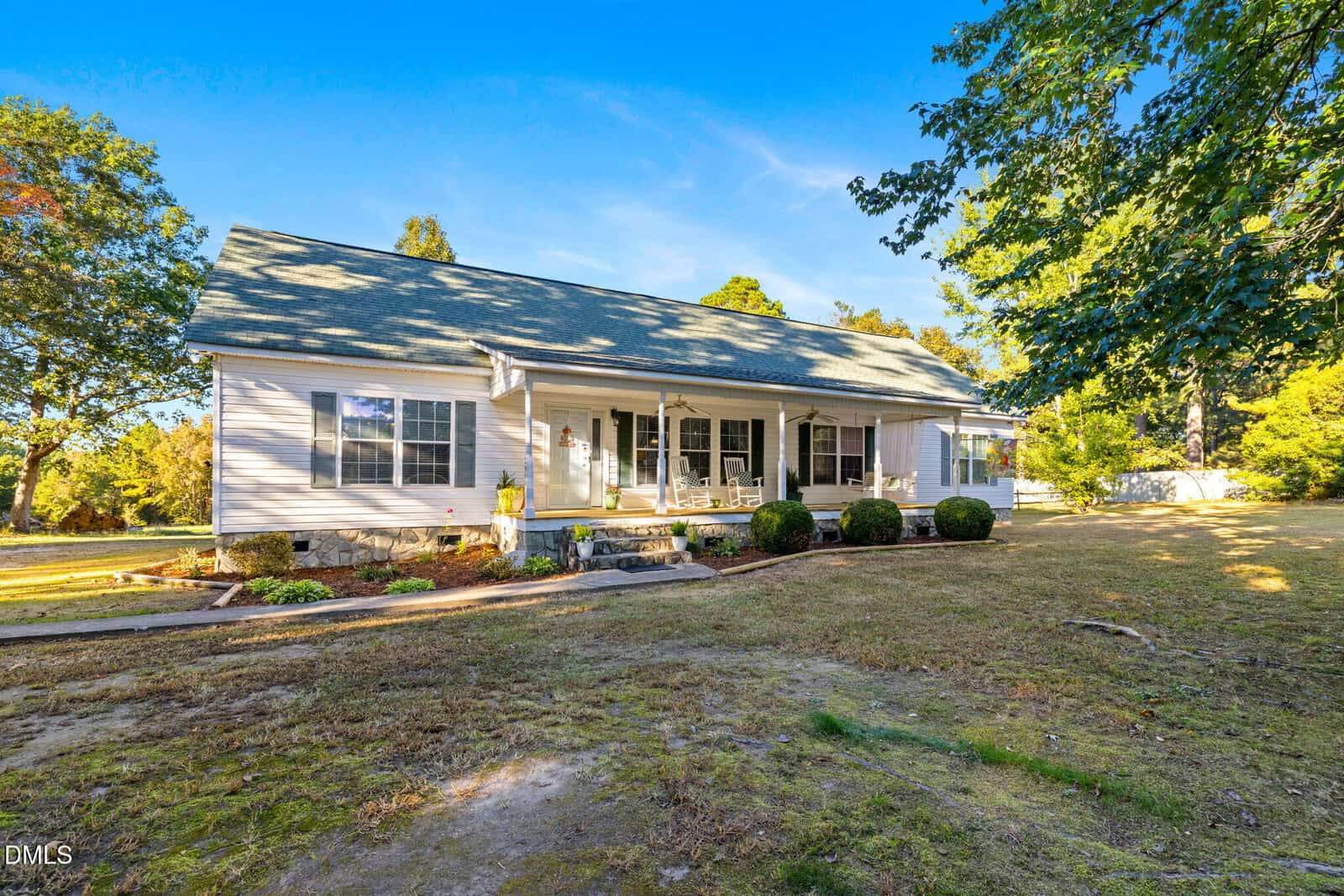 A single-story white house at 3900 Dabney Road, Henderson, with a covered front porch, several windows, a green shingle roof, and a surrounding lawn with trees and shrubs on a sunny day.