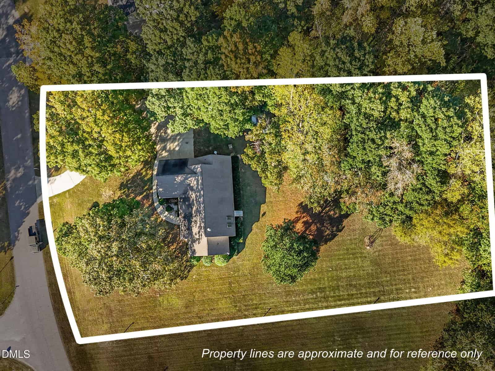 Aerial view of a house surrounded by trees and lawn, with white lines outlining the approximate property boundaries. Text at the bottom states, "Property lines are approximate and for reference only.