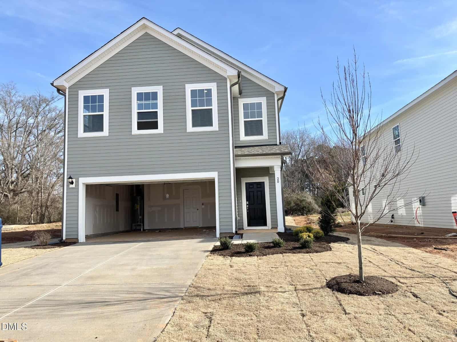 Located in Franklinton, 20 Gerrad Street is a two-story gray house with white trim and a double garage. The front yard features new sod, a small tree, and minimal landscaping, all under a clear blue sky.