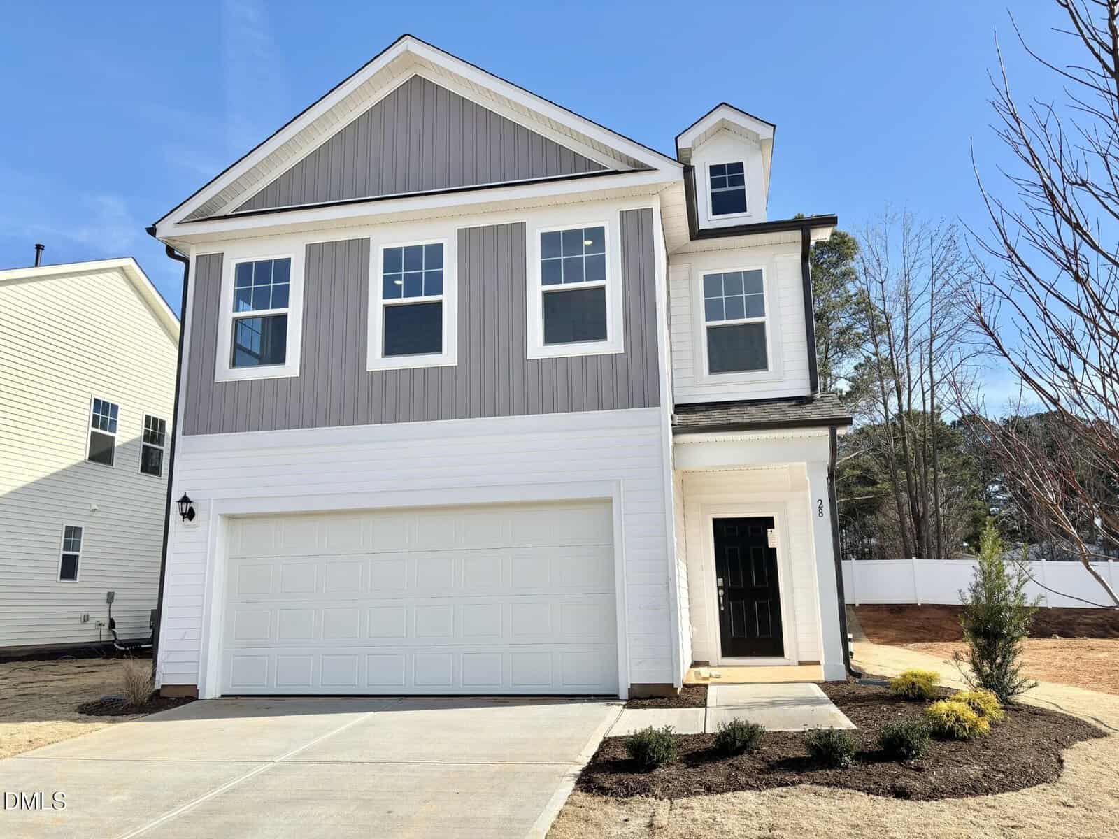 This modern two-story house at 28 Gerrad Street in Franklinton features gray and white siding, multiple front windows, a black door, a two-car garage, fresh landscaping, and a clear blue sky above.