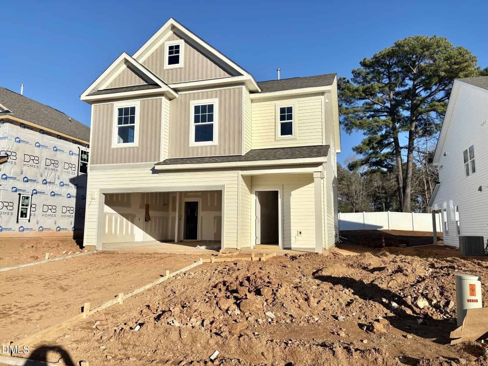 A newly built two-story house at 26 Gerrad Street, Franklinton, features beige siding and a double garage, surrounded by bare, unfinished dirt and construction materials under a clear blue sky.