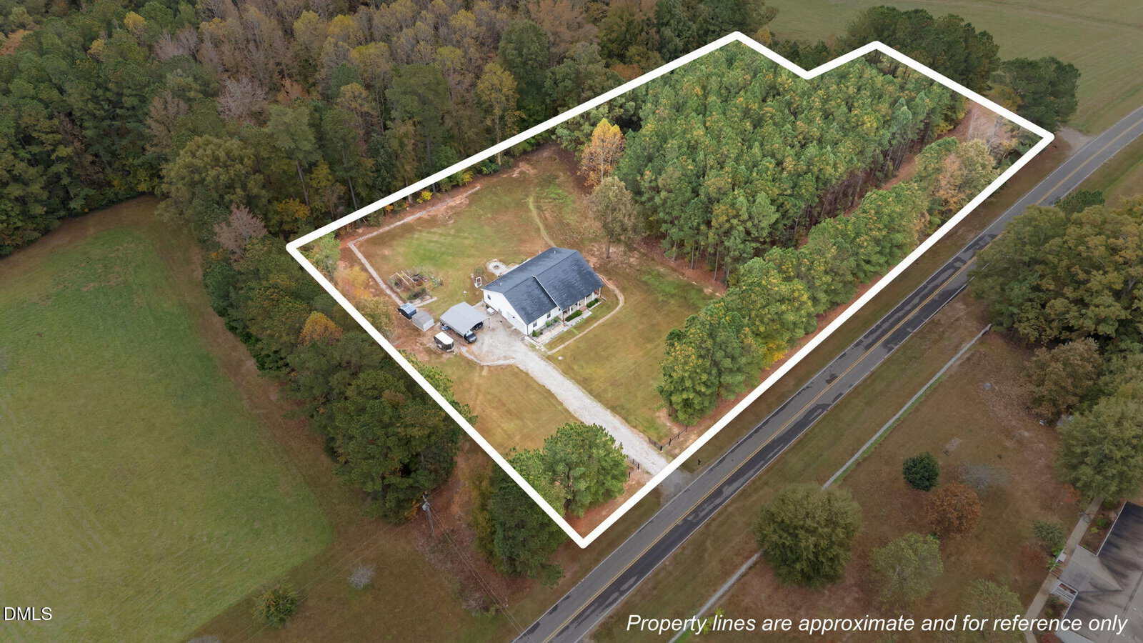 Aerial view of a house with a driveway on a large plot of land surrounded by trees at 457 Reynolds Road, Louisburg; white lines indicate approximate property boundaries. A road runs along one side of the property.