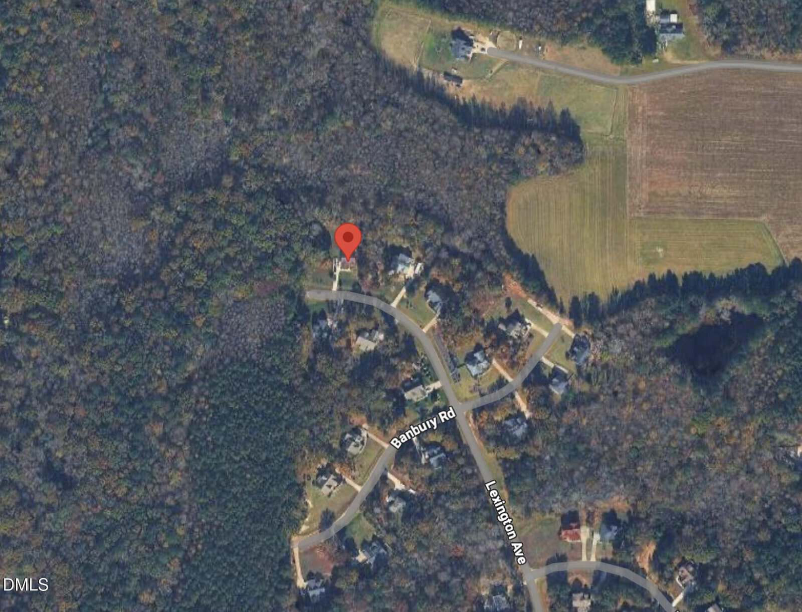 A satellite view of a wooded suburban neighborhood; houses line Banbury Road and Lexington Ave, with a red location pin marking one house. Surrounding areas include dense trees and open fields.