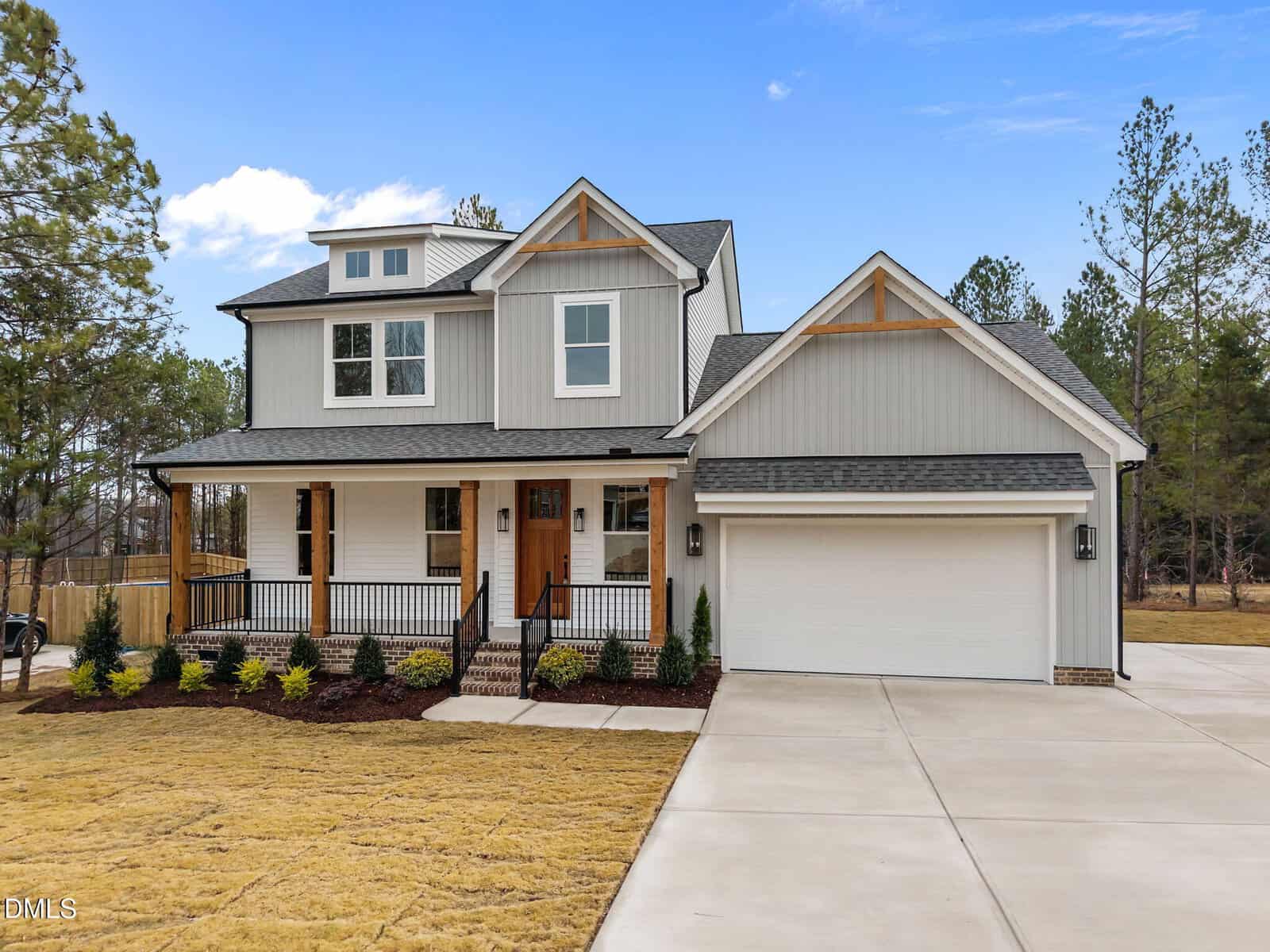 Modern two-story house at 30 Vino Trail, Franklinton, with gray siding, white trim, covered front porch, wooden accents, and a double garage. The home features a landscaped yard and sits beside a wooded area under a clear blue sky.