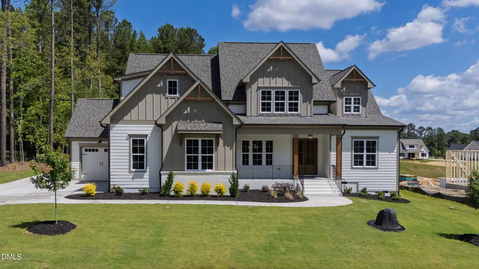 A modern two-story house at 55 Broadleaf Lane in Youngsville with gray siding, white trim, and a covered front porch. The home is surrounded by green lawn, young plants, and trees under a blue sky with clouds.