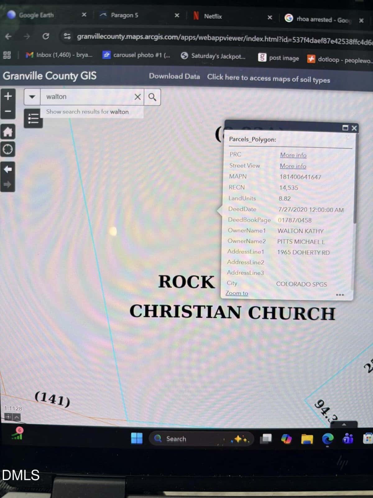 A computer screen displays the Granville County GIS map with a parcel information window open, showing property details for a location near "Rock Christian Church." Laptop keys are visible at the bottom.