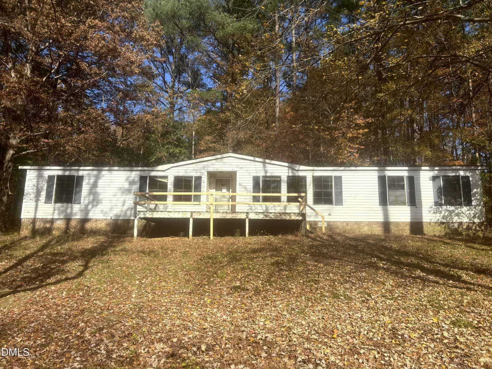 A single-story white house with black shutters sits in a wooded area at 4131 Morton Lane, Franklinton. The home features a central front porch with a wooden railing and steps, surrounded by trees with autumn leaves on the ground.