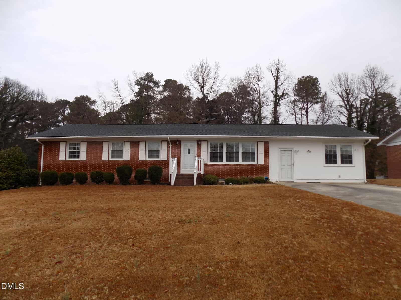 Single-story brick and white-sided house with a dark roof, front porch with steps, neatly trimmed bushes, and a large brown lawn at 212 Allen Lane in Louisburg. Leafless trees and a gray sky are visible in the background.