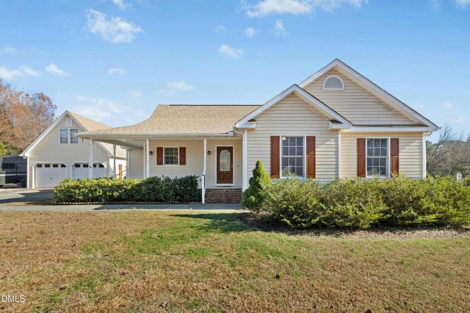 Charming single-story beige house at 160 Glenmore Circle in Youngsville with brown shutters, a covered front porch, and an attached two-car garage. The yard features grass and shrubs under a clear sky with a few clouds.