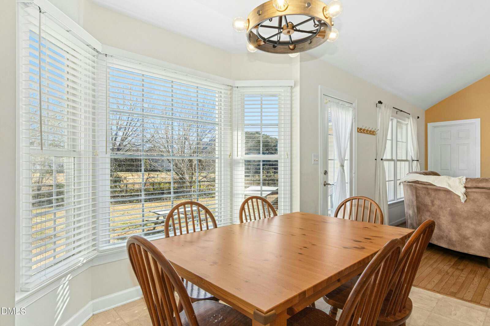 A dining table and chairs in a room with blinds.