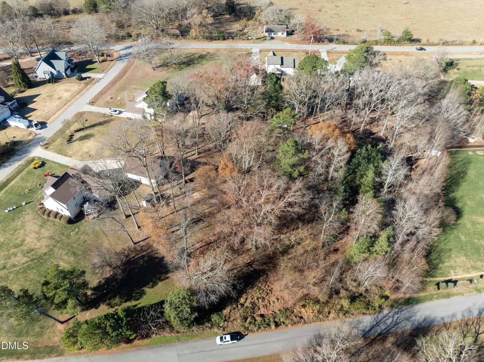 Aerial view of a Wake Forest suburban neighborhood with several houses, leafless trees, grass lawns, and main roads at the top and bottom. A white car is parked on the lower road near 1039 Heather Lane.