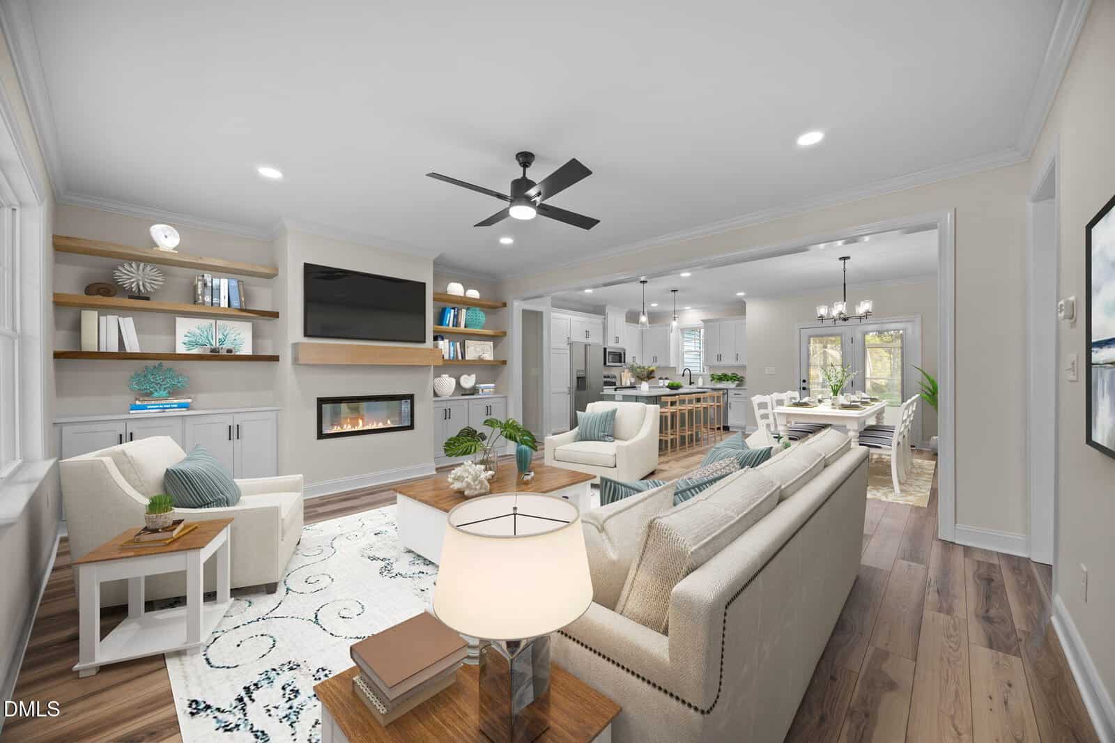 Modern open-concept living room with neutral decor, a cozy fireplace under a wall-mounted TV, built-in shelves, light wood floors, and a kitchen and dining area visible in the background.