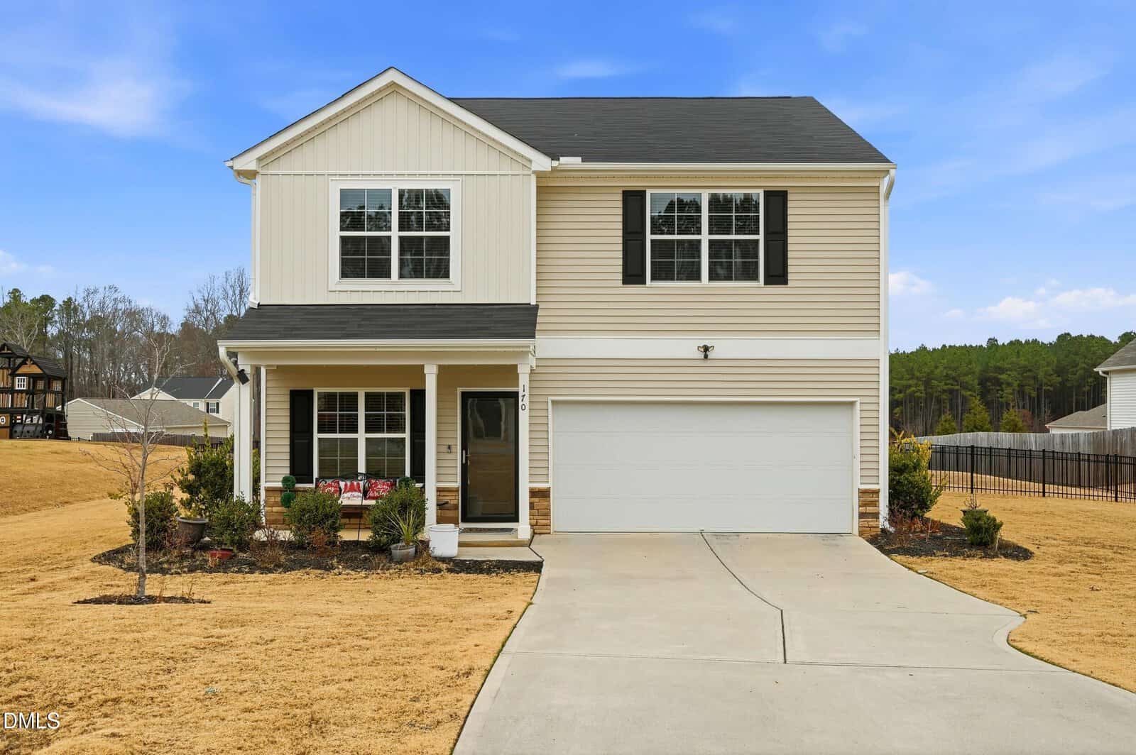 Two-story beige house at 170 Gill Farm Way in Franklinton, featuring black shutters, a two-car garage, covered front porch, and paved driveway. The yellowed lawn is bordered by shrubs, with neighboring houses and trees in the background.
