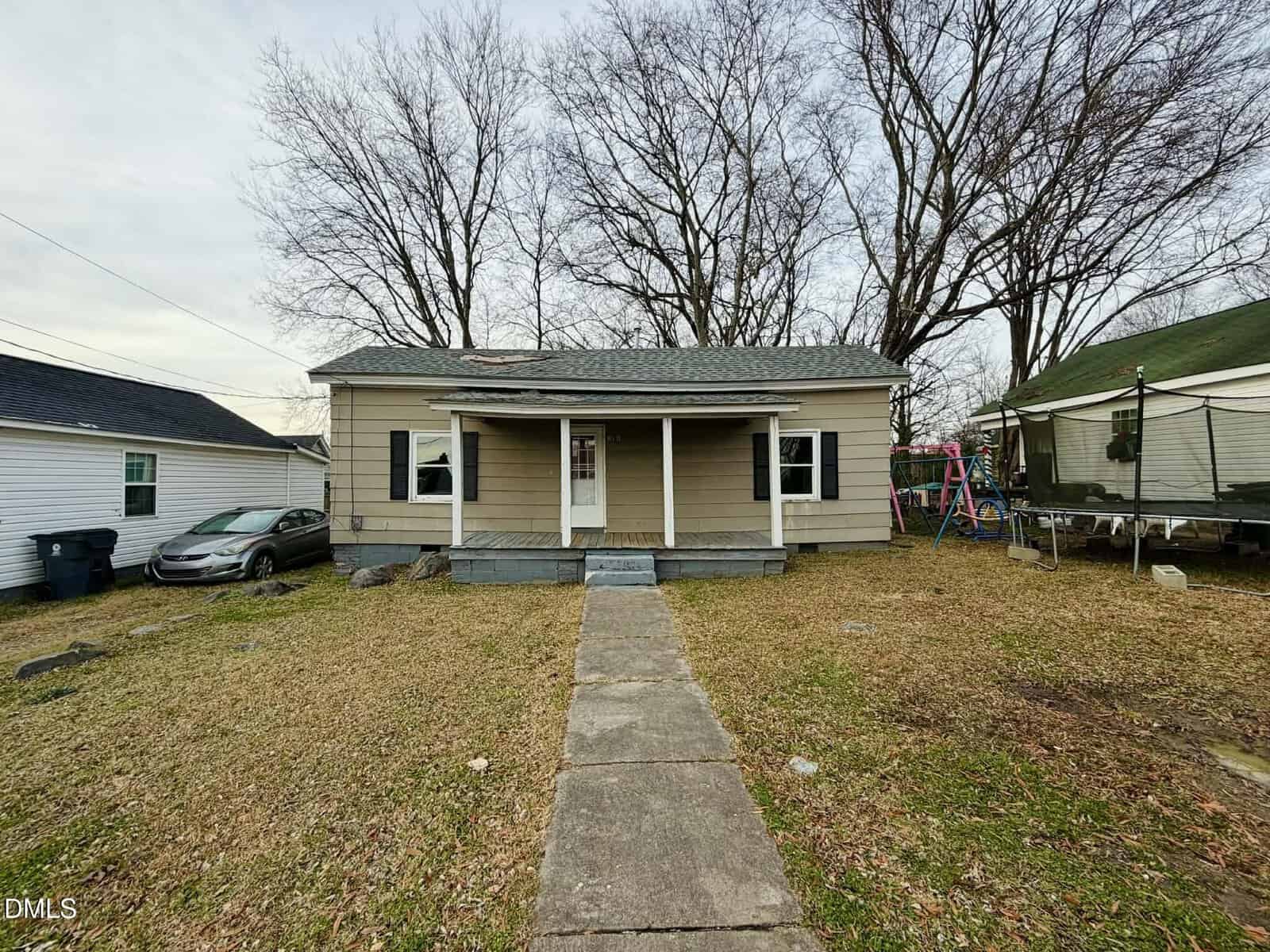 Charming single-story beige house with a gray roof at 316 Piedmont Avenue, Oxford. Features two front columns, a concrete walkway to the entrance, leafless trees behind, a car on the left, and a trampoline on the right.