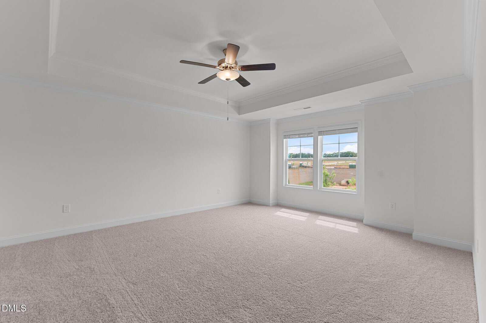 Bright empty room with light carpet, white walls, a ceiling fan, and three large windows letting in natural light.