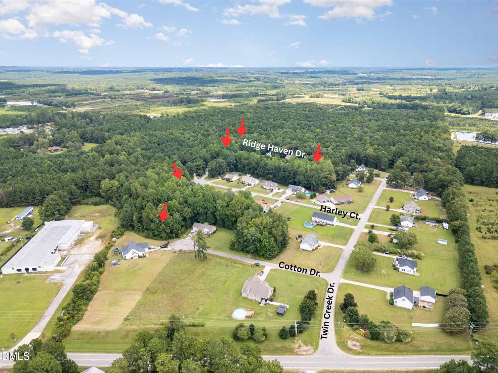 Aerial view of a suburban neighborhood in Louisburg with scattered houses, roads, and green spaces. Red arrows point to 60 Ridge Haven Drive, with nearby streets labeled as Harley Ct., Cotton Dr., and Twin Creek Dr. Forested areas surround the neighborhood.