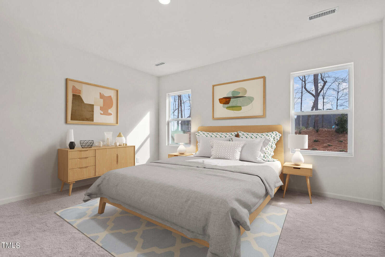 Bright bedroom with a large bed, light wood furniture, abstract art on white walls, gray carpet, two windows letting in natural light, and a soft geometric rug under the bed.