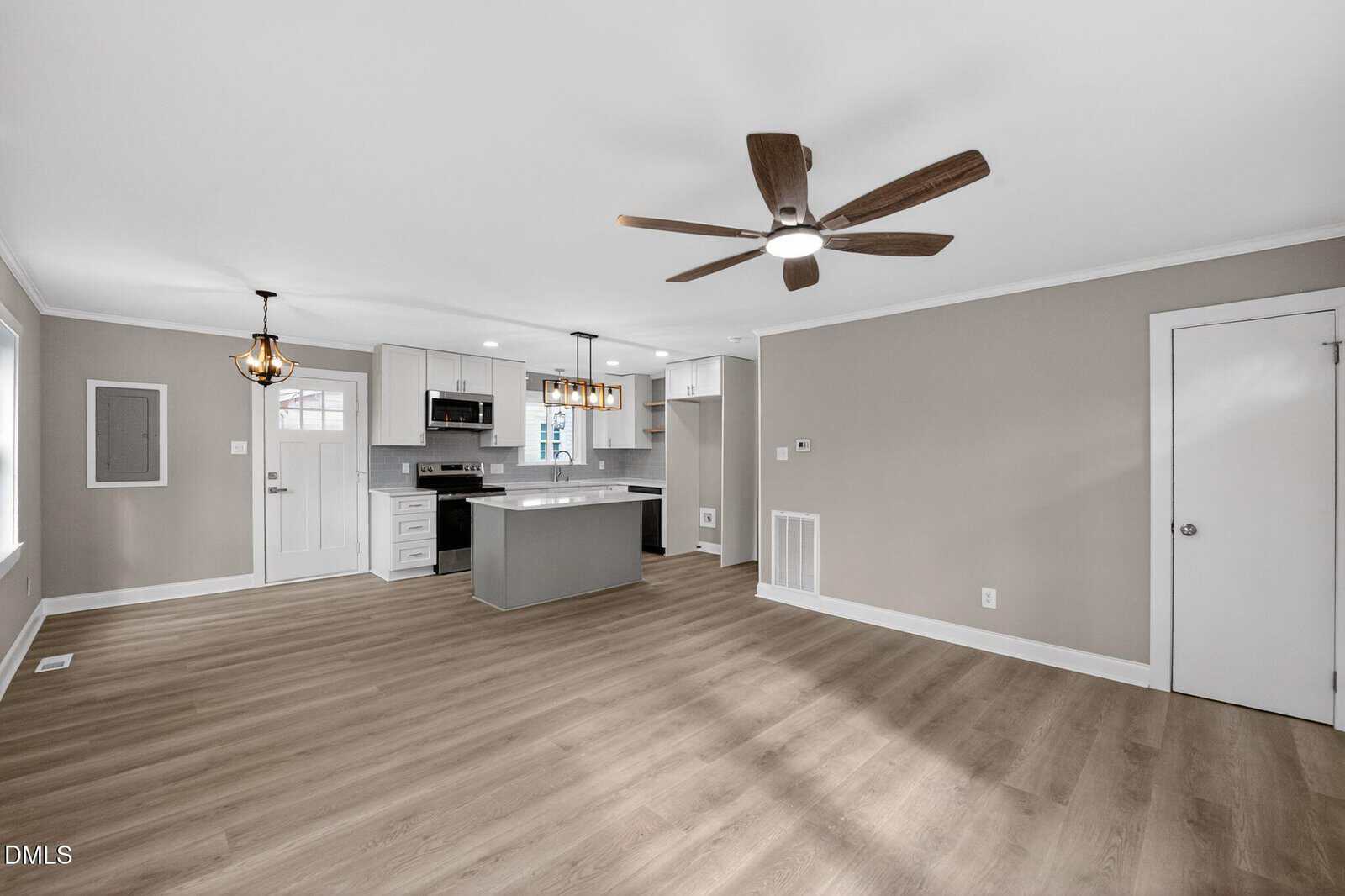 Open concept kitchen and living area with light wood flooring, beige walls, white trim, ceiling fan, recessed lighting, modern appliances, a central island, and large windows providing ample natural light.