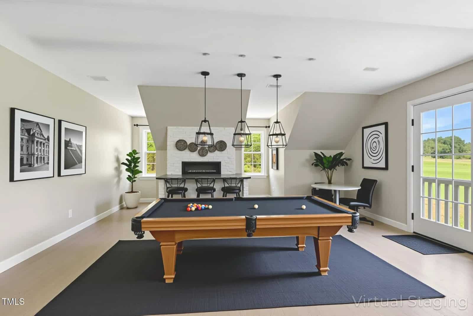 A modern game room with a pool table on a black rug, three pendant lights above, a seating area with two chairs and a round table, wall art, a fireplace, and a door leading outside. Bright and neutral decor.